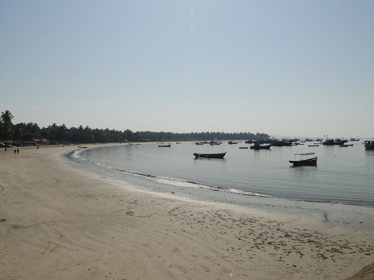 The long curve of Malvan beach with boats at anchor