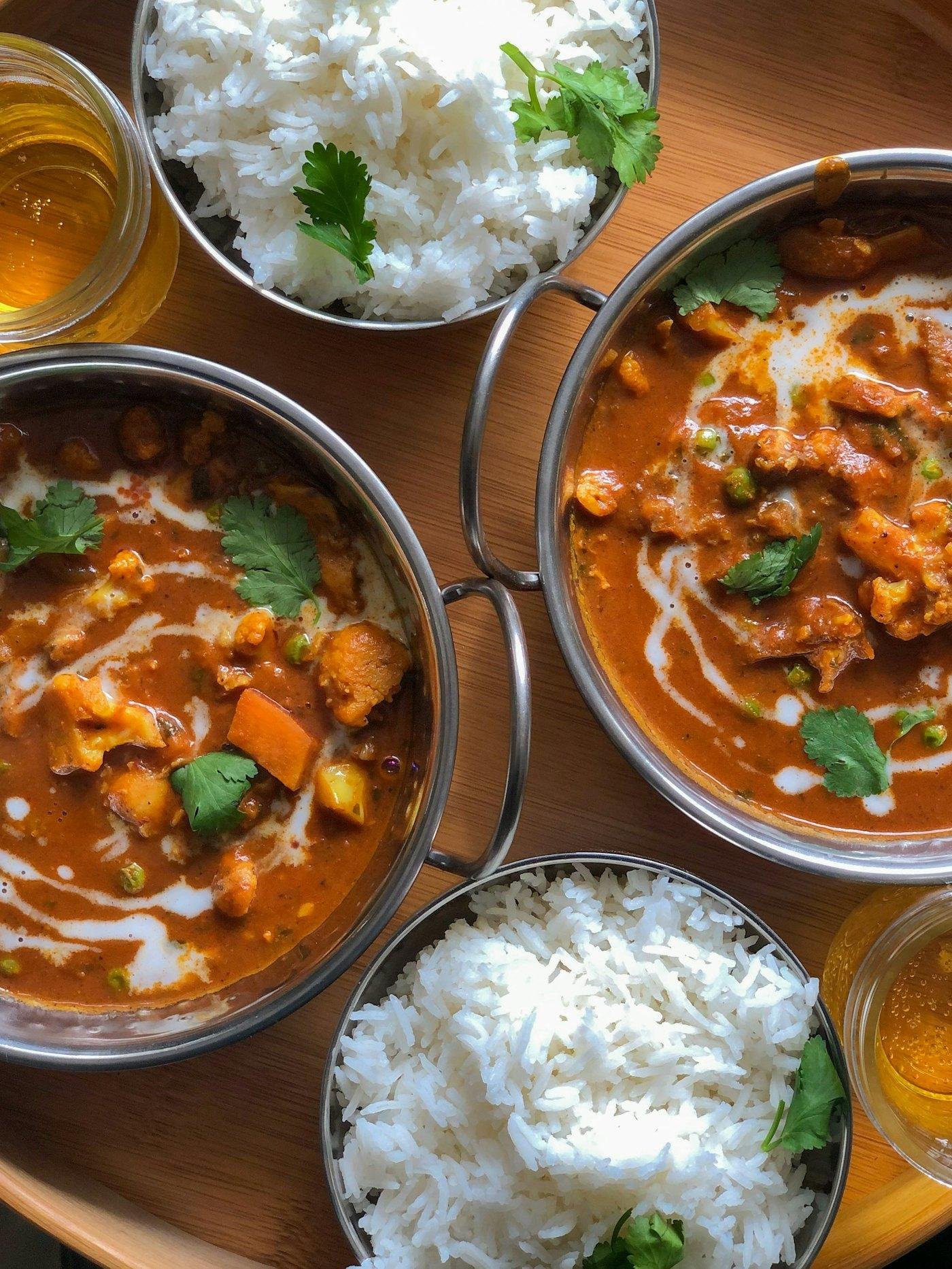 Bowls of curry, rice and bread laid out for a meal